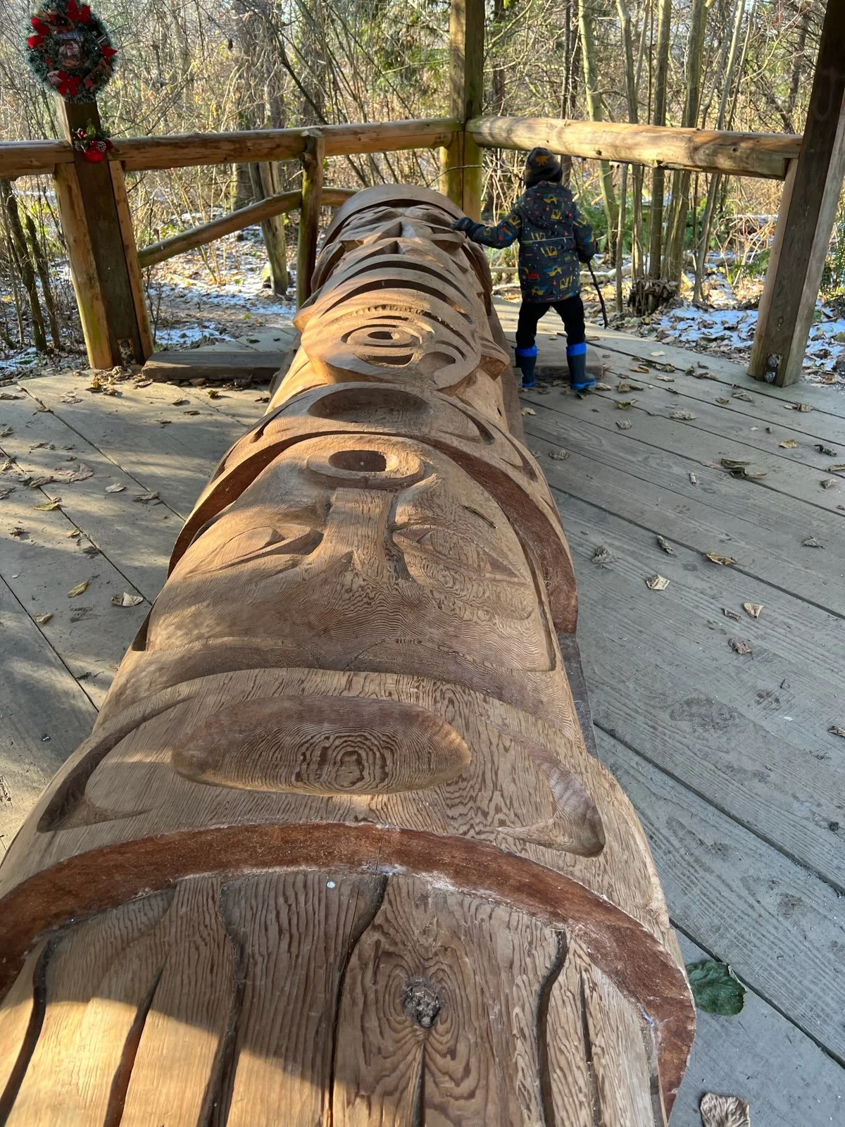 A child reaches out to touch a carved cedar totem